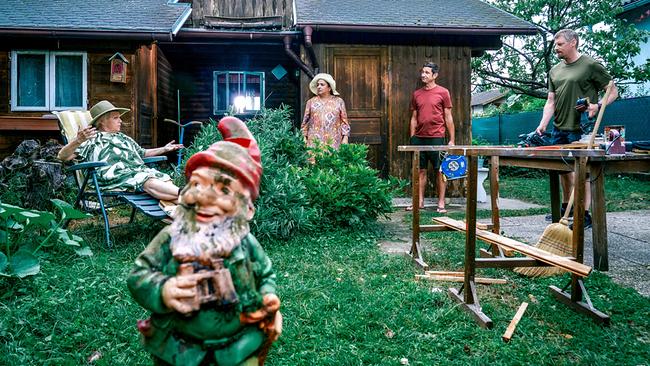 Vor einem Holzhaus liegt Henriette Wolf in einer Gartenliege, daneben stehen Franziska Beck sowie Klaus Lechner mit einer Kabeltrommel und Max Herzog vor einem Arbeitstisch. Im Vordergrund steht ein Gartenzwerg.