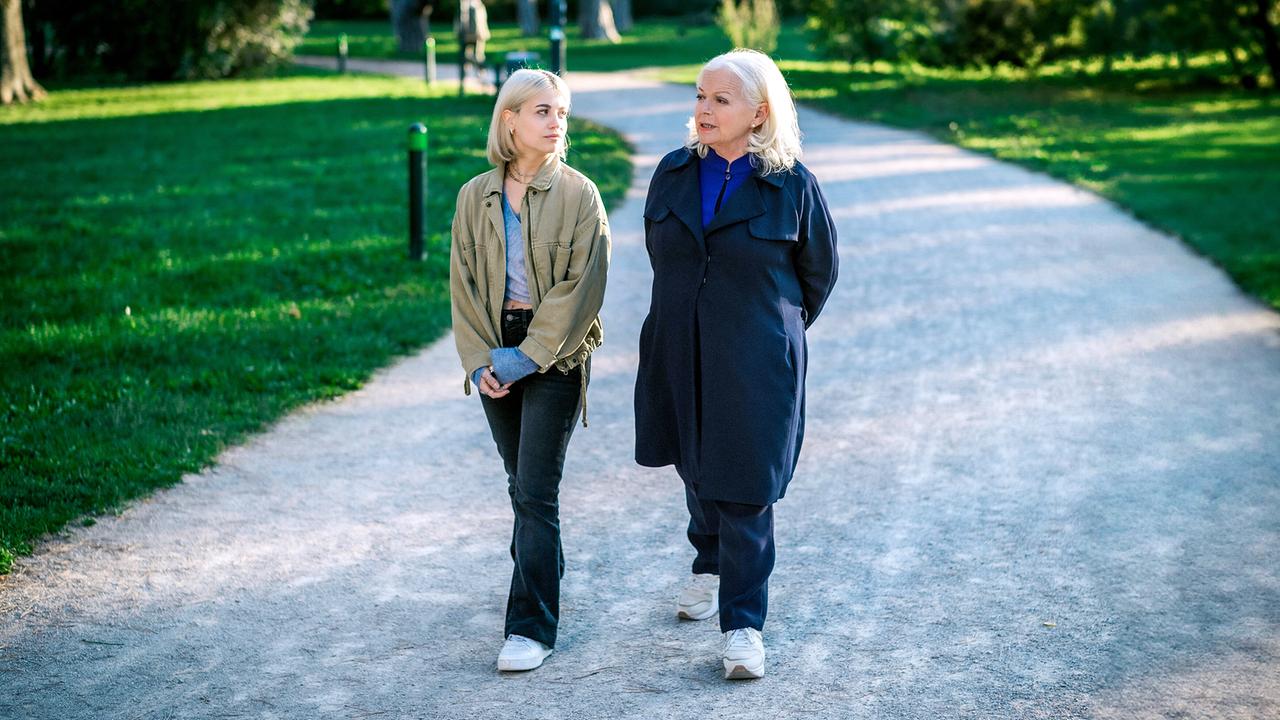 Lea Schlatterer und Henriette Wolf spazieren nebeneinander auf einem Parkweg und unterhalten sich in ruhiger Umgebung.