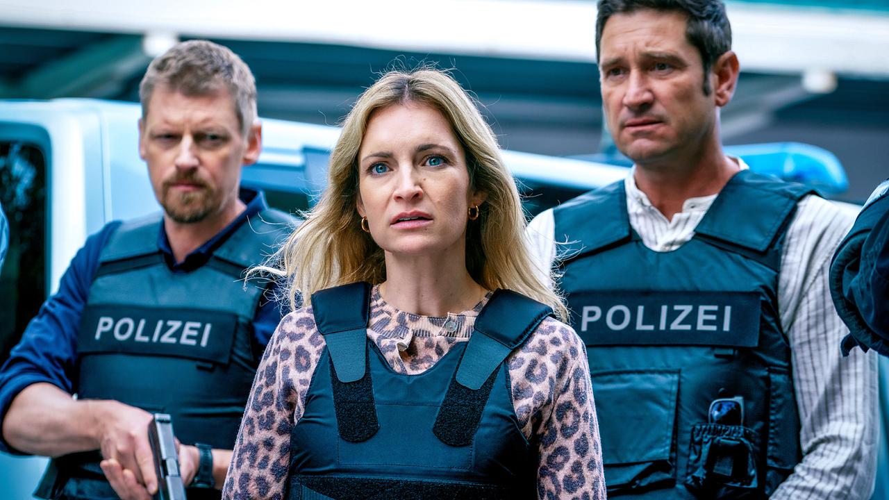 © ORF/Satel Film/Petro Domenigg Silvia Tillmann in Schutzweste steht zwischen den beiden Polizisten Max Herzog und Klaus Lechner ebenfalls in Schutzwesten, die sie flankieren und sichern.