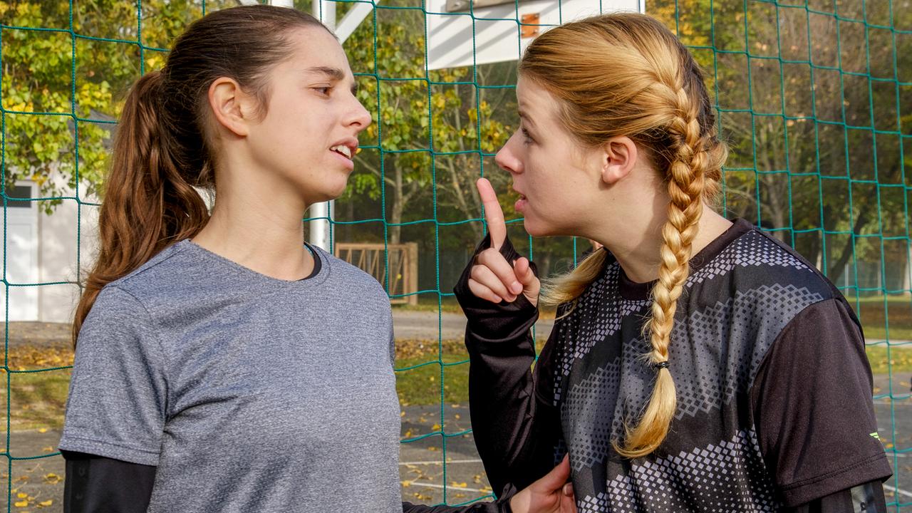 Die Fußballspielerinnen Emily und Kira stehen sich im Freien gegenüber, Kyra streckt ihr dabei mahnend den Zeigefinger entgegen.