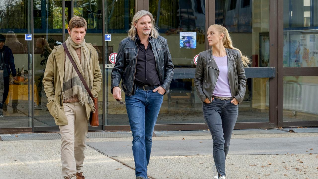 Klaus, Carl und Penny gehen gemeinsam aus einem Gebäude und unterhalten sich.