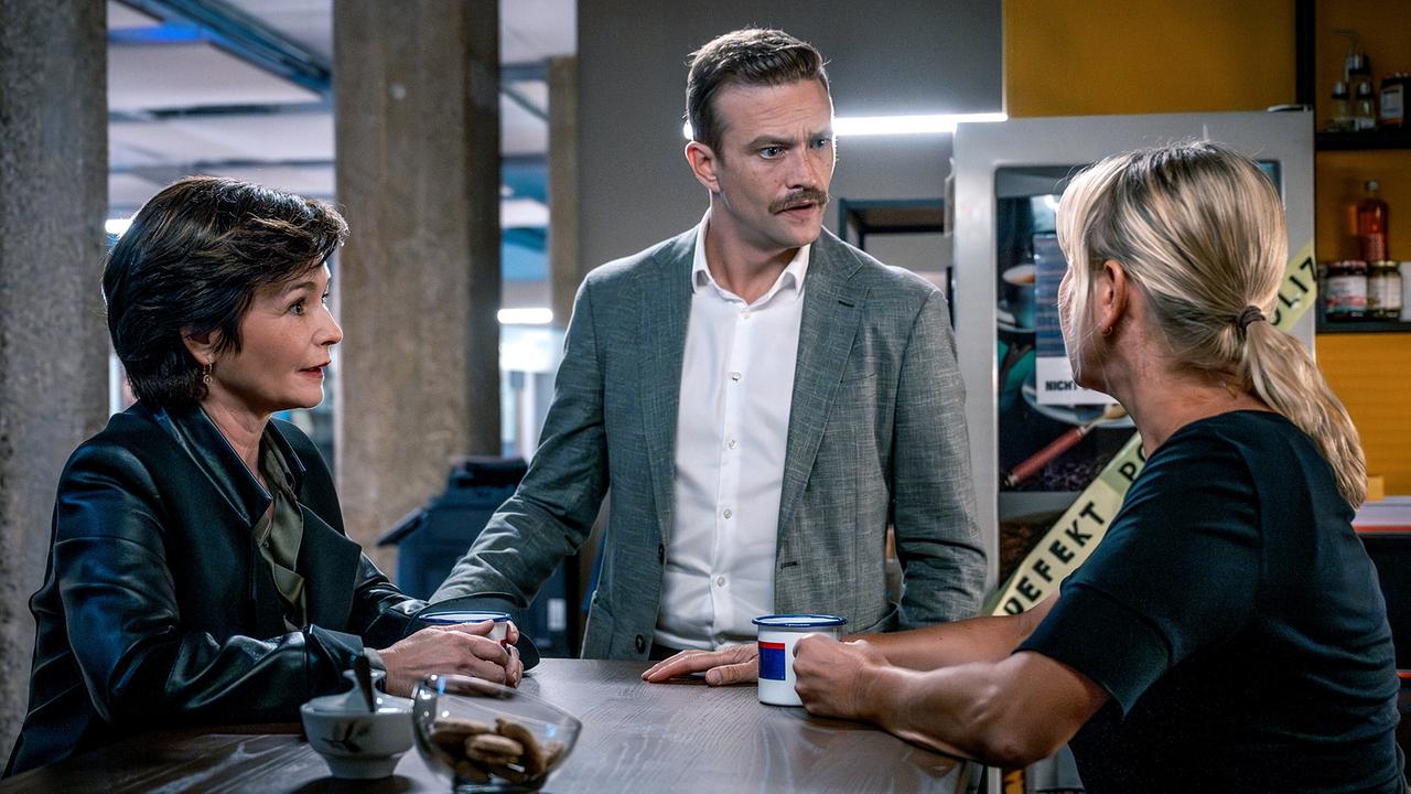 Katharina Stemberger, Michael Steinocher und Angelika Niedetzky mit Kaffee am Tisch vor einem Kaffeeautomaten