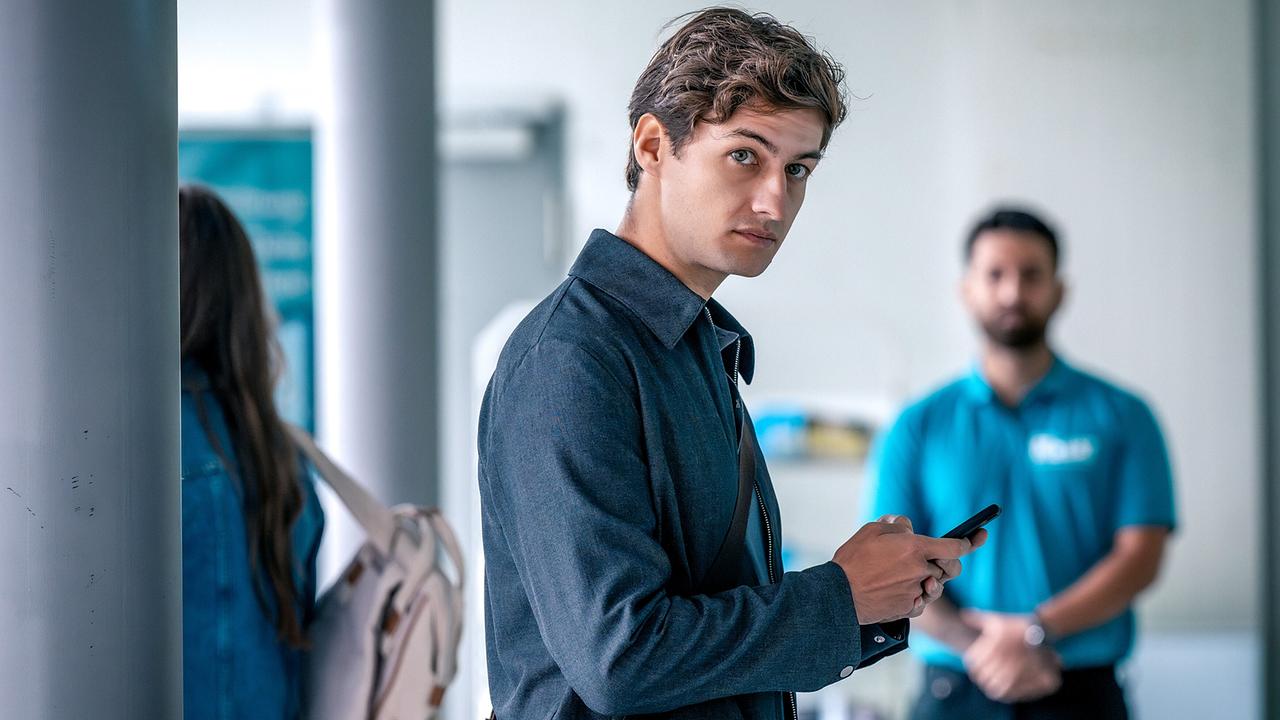 Anton Widauer mit Smartphone in der Hand in einem modernen Gebäude blickt auf etwas