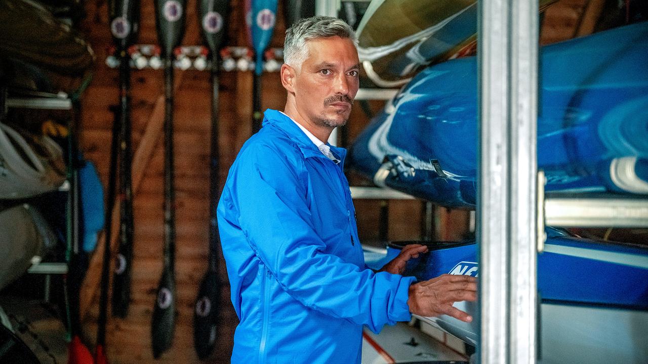 Faris Rahoma in einem Bootshaus berührt ein gelagertes Ruderboot.