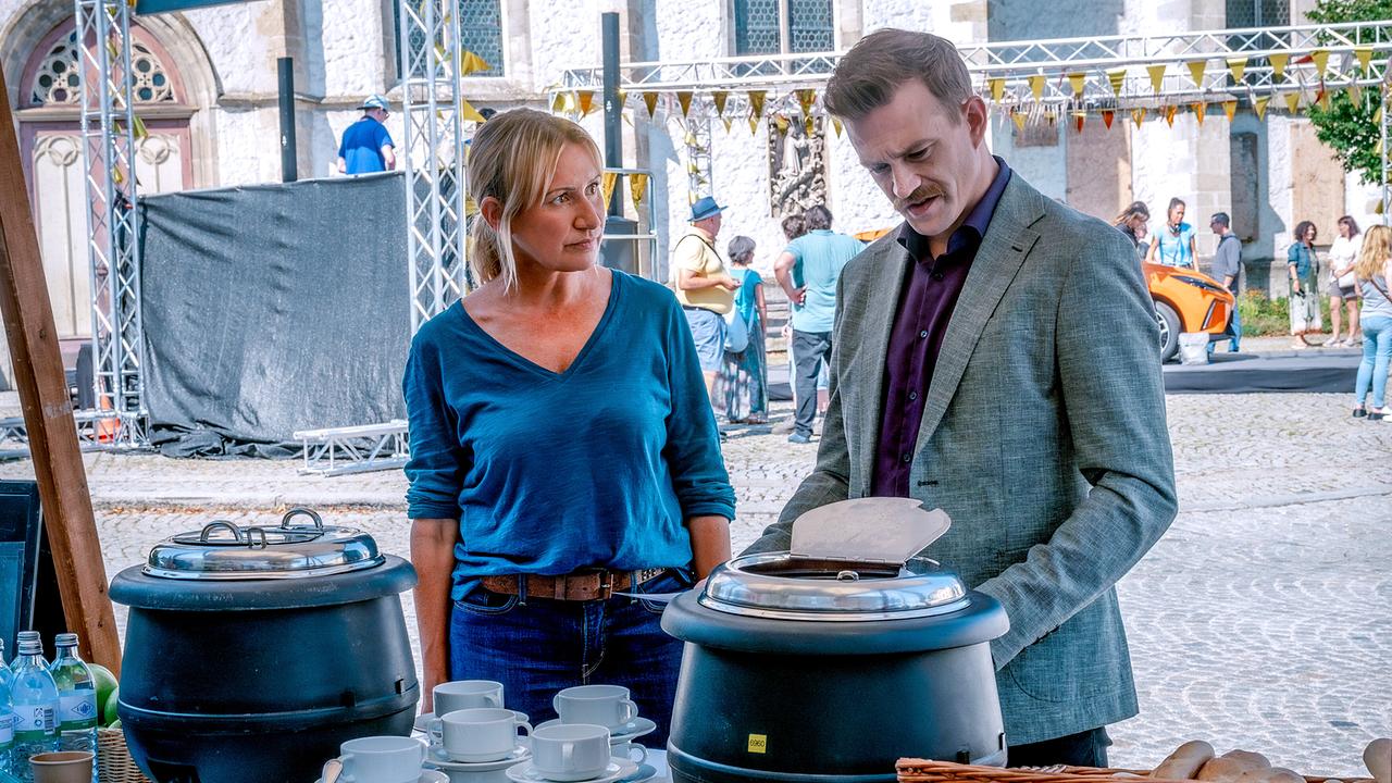 Angelika Niedetzky und Michael Steinocher stehen hinter einem Tisch mit Suppentöpfen, Tassen und Pappbechern bei einer Veranstaltung im Freien.