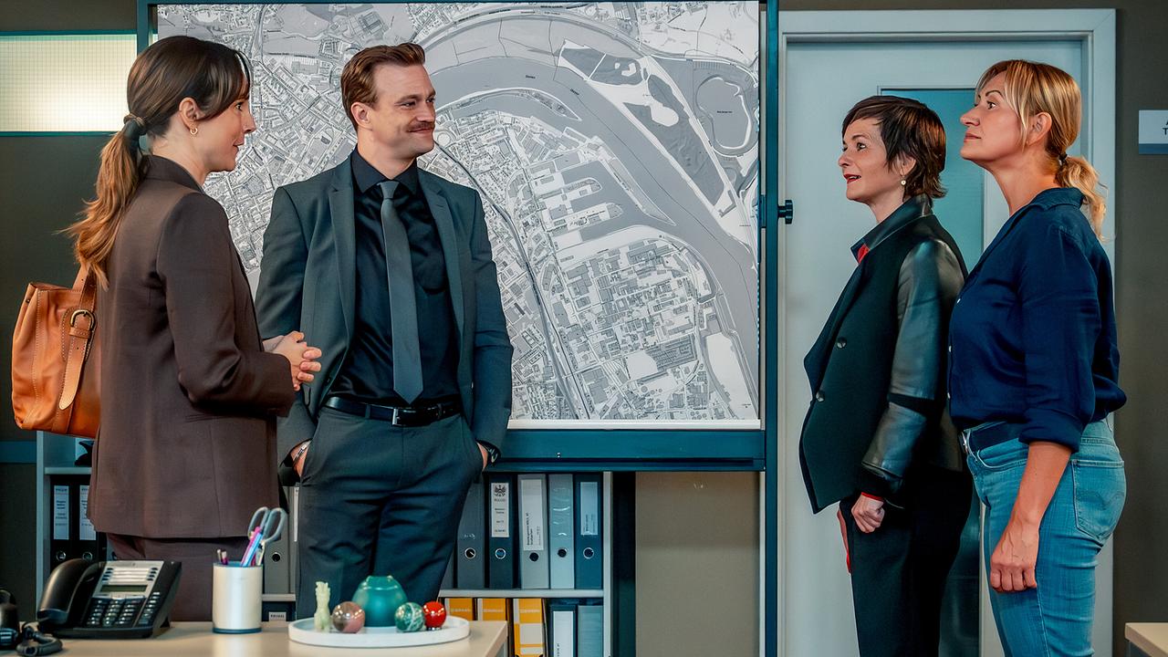 © ORF/Gebhardt Productions/Stefanie Leo Patrizia Specht, Stefan Pichlwanger, Joe Haizinger und Biggi Obergschwendter stehen vor einem großen Stadtplan im Büro und unterhalten sich.