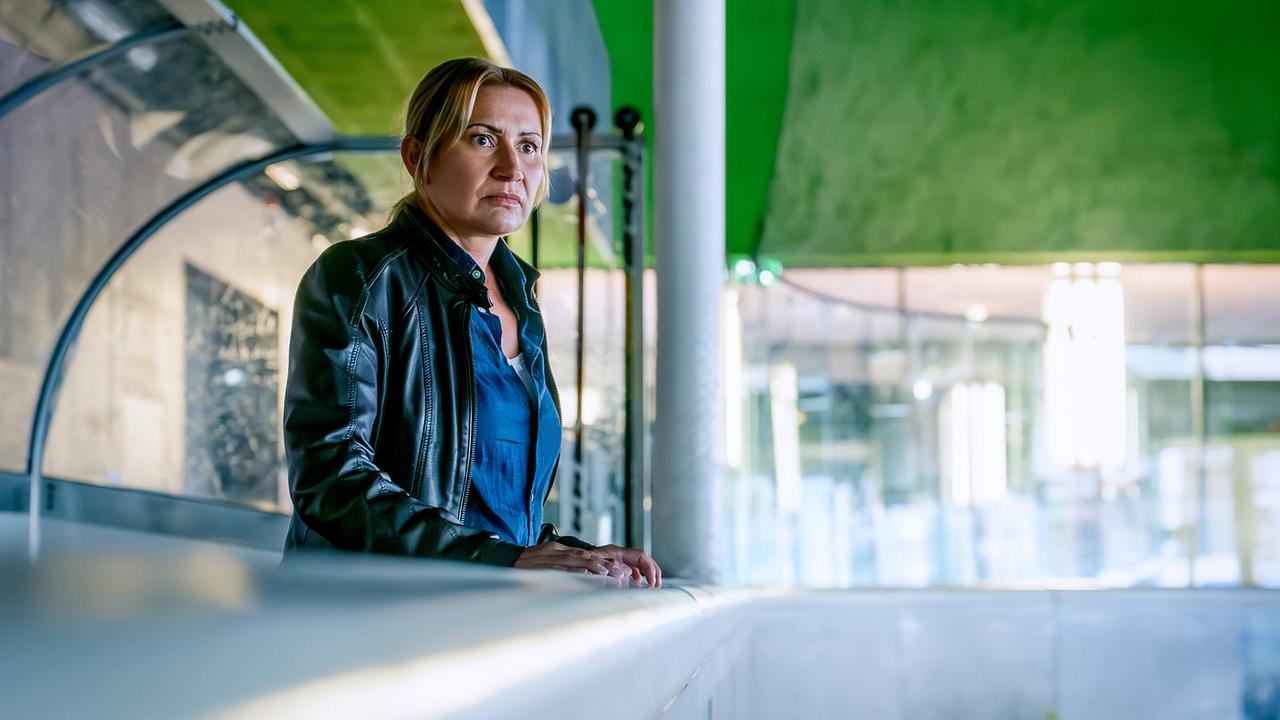© ORF/Gebhardt Productions/Stefanie Leo Biggi Obergschwendter in Lederjacke steht nachdenklich an der Bande einer Eishalle.