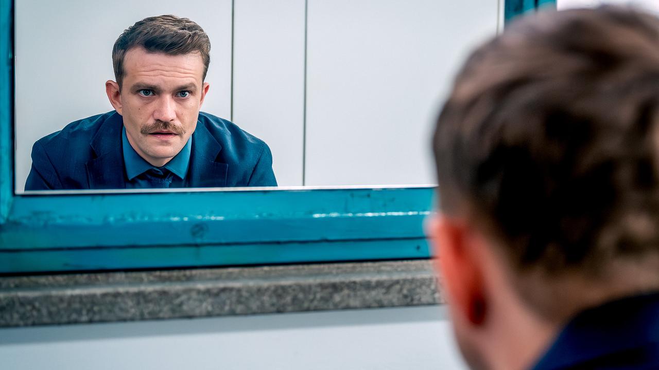 Stefan Pichlwanger betrachtet sich mit ernstem Blick in einem Spiegel.
