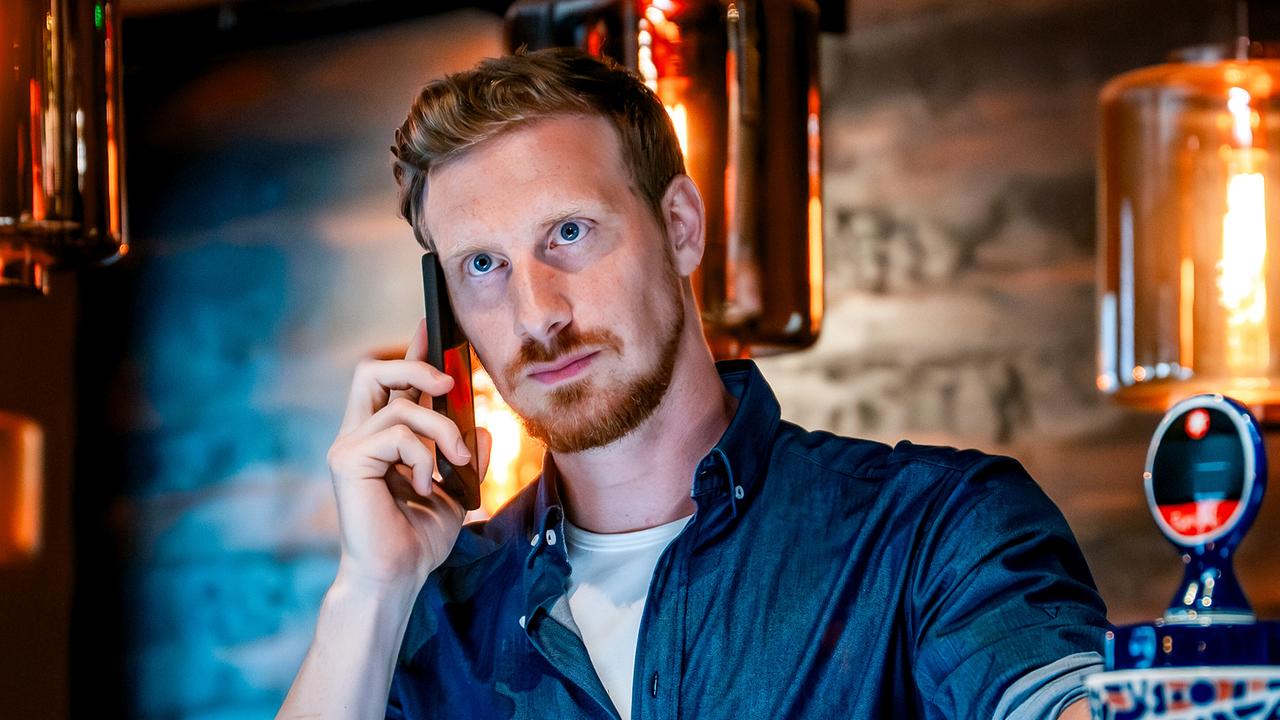 Walter Obergschwendter telefoniert hinter der Bar am Handy.