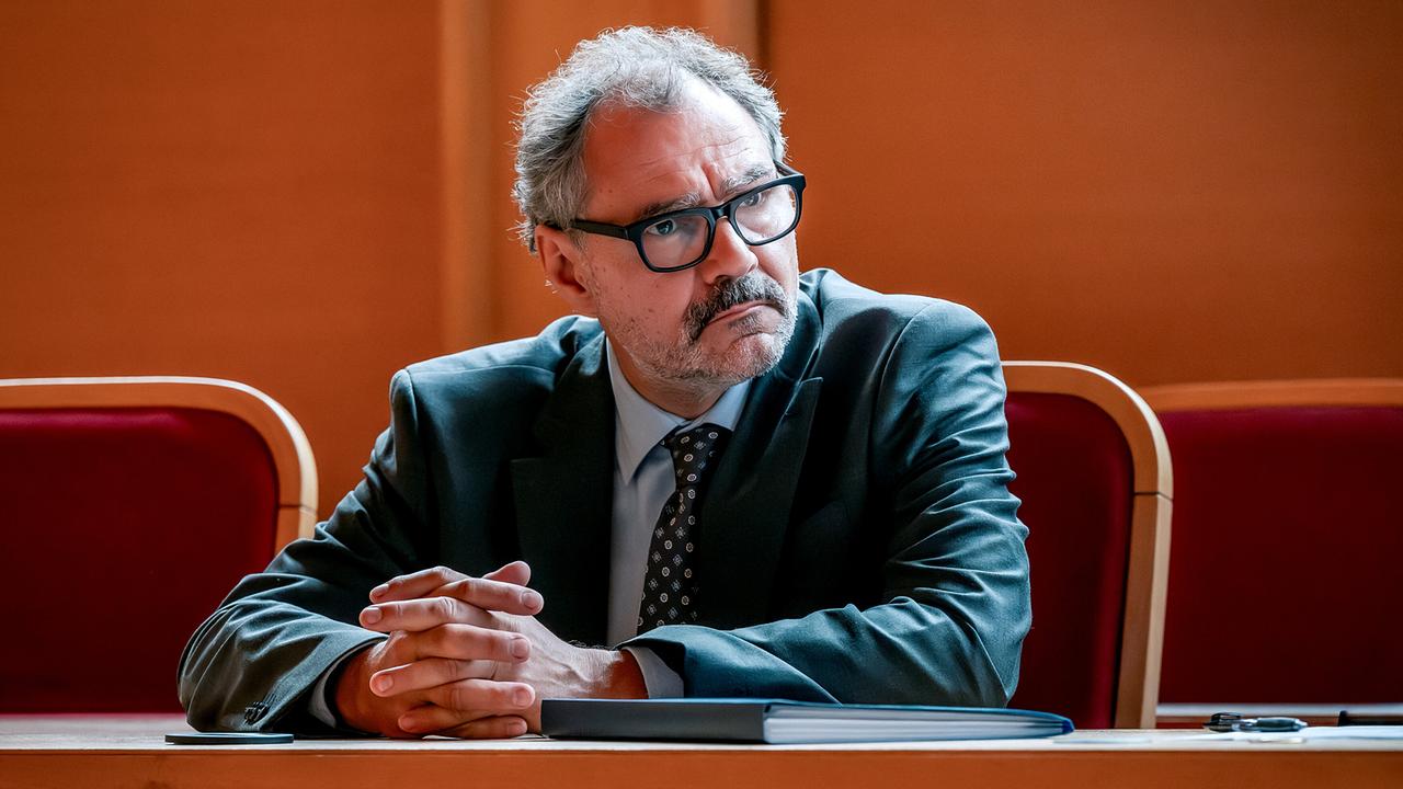Anwalt Ernst Unterpertinger mit Brille sitzt konzentriert an einem Tisch im Gerichtssaal.