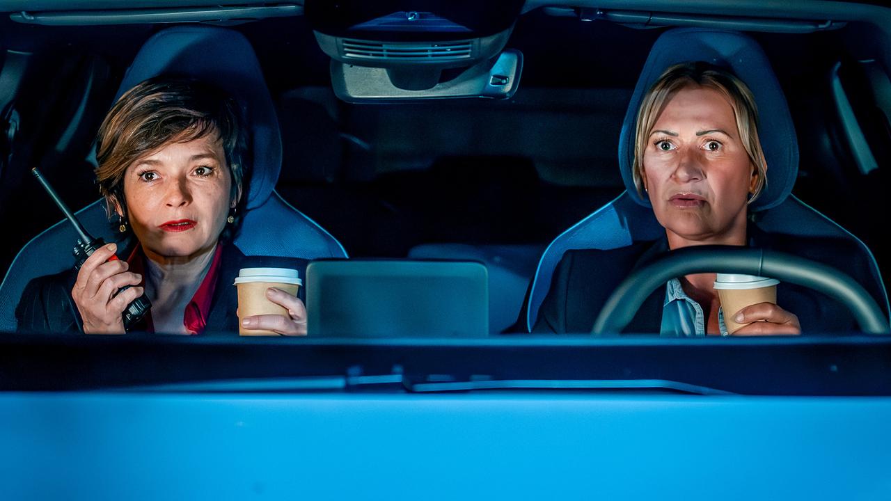 © ORF/Gebhardt Productions/Stefanie Leo Joe Haizinger mit einem Funkgerät in der Hand und Biggi Obergschwendter sitzen angespannt nachts im Auto.
