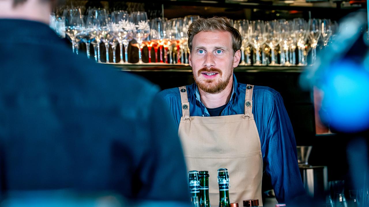Walter Obergschwendter spricht hinter einer Bar mit jemandem vor ihm.