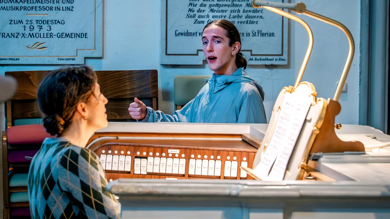 Enno Tomberg singt an einer Orgel in einem historischen Gebäude, während Isolde Überbacher ihn an der Orgel begleitet.