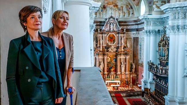 Joe und Biggi stehen auf einer Empore und blicken in das prunkvolle Innere der barocken Stiftskirche St. Florian.