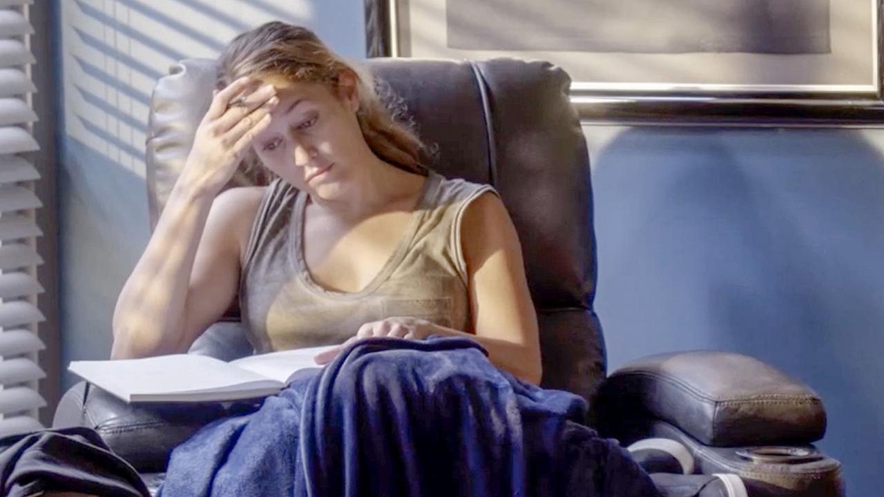 © ORF/Disney/ABC Eine Frau sitzt in einem Sessel, Andy Herrera stützt ihren Kopf in die Hand und hat ein aufgeschlagenes Buch vor sich – sie wirkt nachdenklich