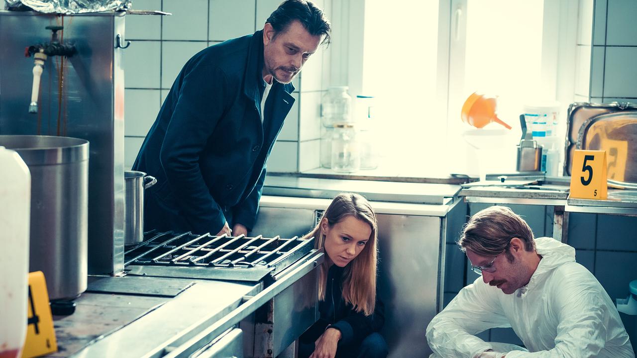 Sascha Bergmann, Anna Unterberger und Forensiker Bernd Kofler untersuchen eine Spur unter einer Küchenzeile am Tatort.