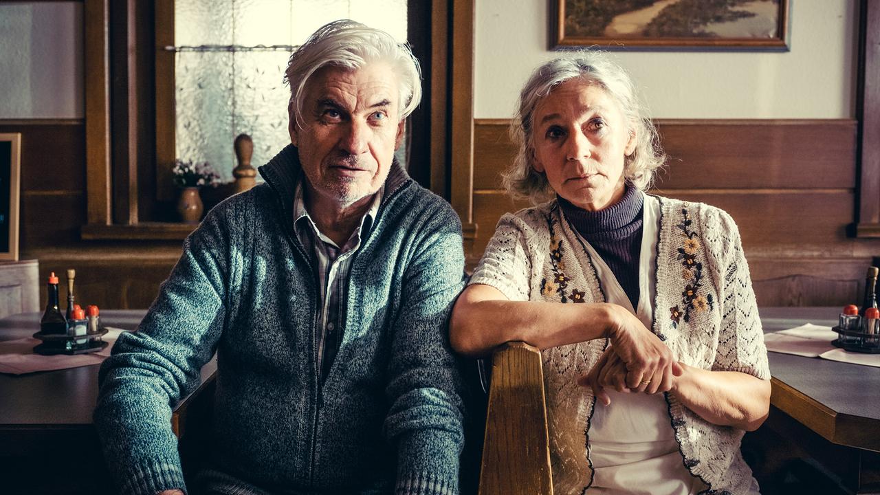 Hermann und Silvia Gruber sitzen in einer gemütlichen Stube nebeneinander und blicken in eine Richtung.
