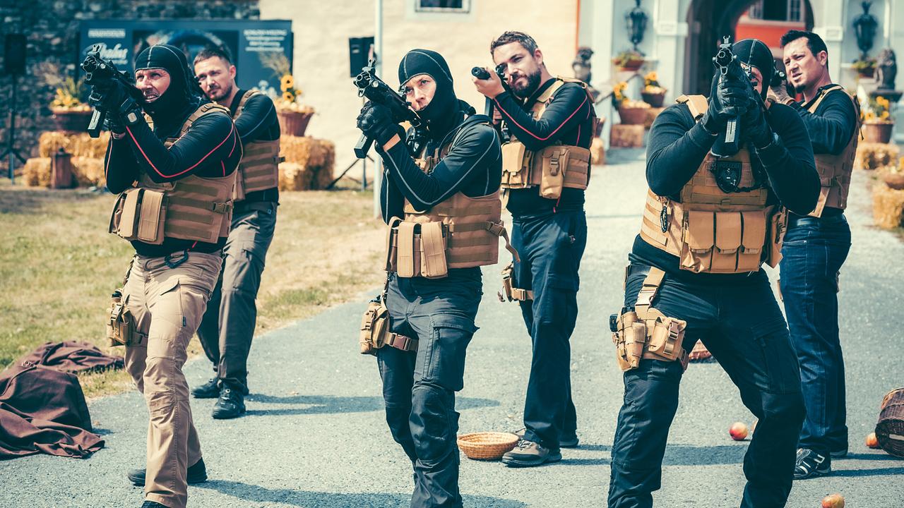 Männer in taktischer Ausrüstung mit Waffen zielen in einer Freiluftszene.