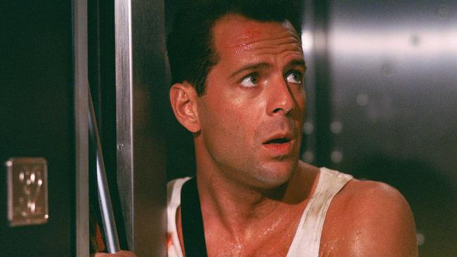 © ORF/Disney Bruce Willis als John McClane - im weißen Trägershirt steht er in einem Lift, hält die Türe mit einer Stange auf und blickt stirnrunzelnd nach oben