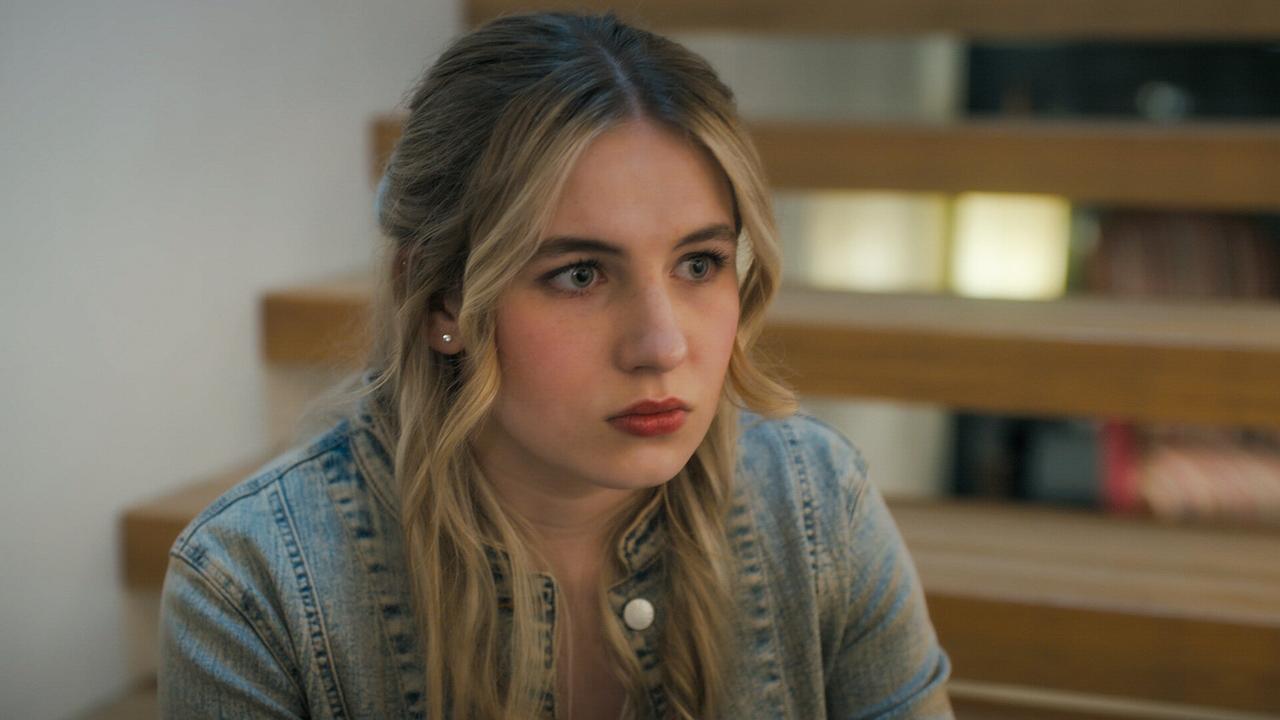 © ORF/MR Film Niobe Eckert in Jeansjacke sitzt vor einer modernen Holztreppe.