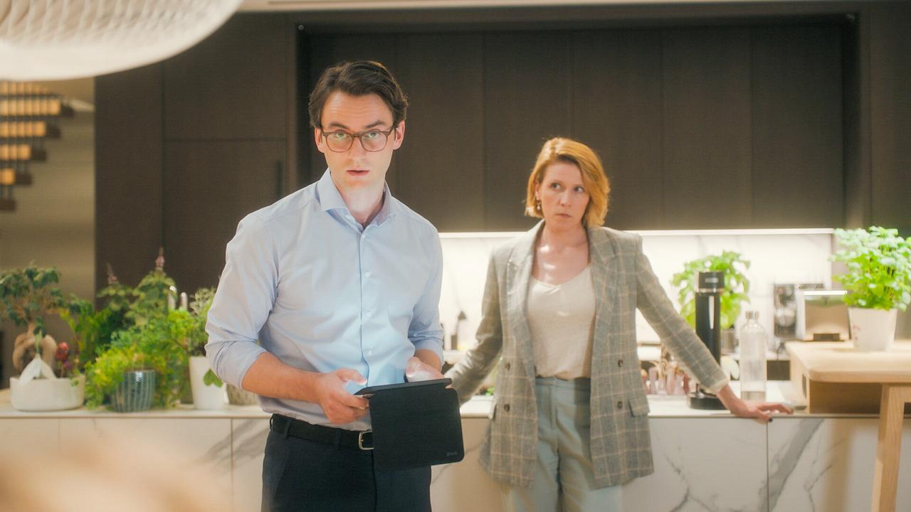 © ORF/MR Film Tobias Resch steht mit einem Tablet, während Franziska Weisz in einer modernen Küche daneben lehnt.