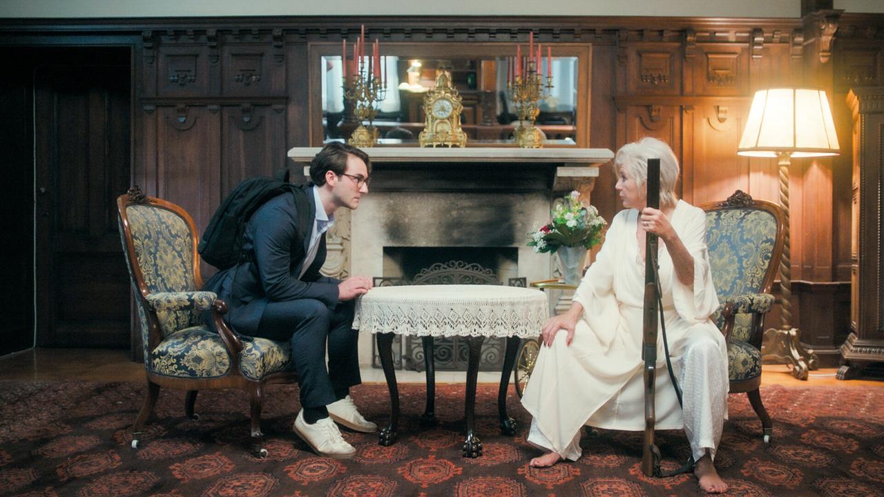 © ORF/MR Film Tobias Resch unterhät sich mit Jutta Speidel, die ein Gewehr in der Hand hält, in einem prunkvollen Raum mit Kamin und antiken Möbeln