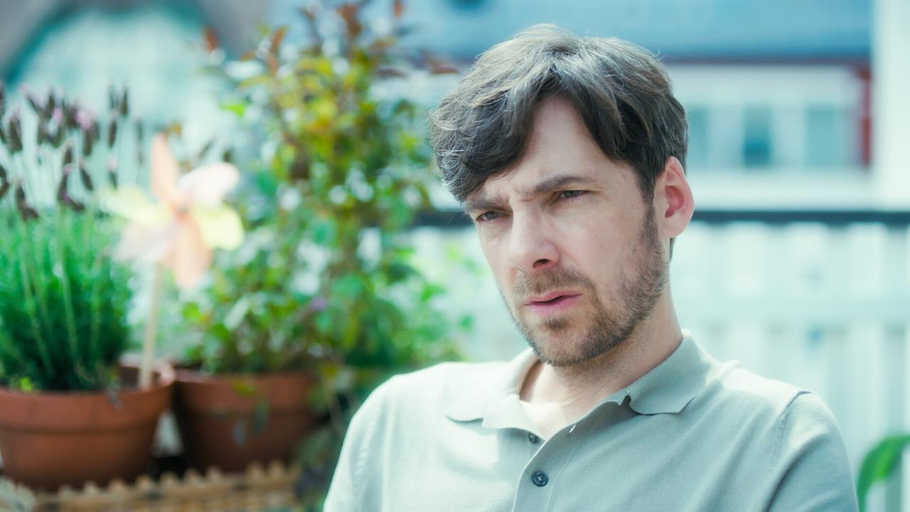 © ORF/MR Film Stefan Pohl sitzt auf einem Balkon mit Pflanzen und Dekoration im Hintergrund.