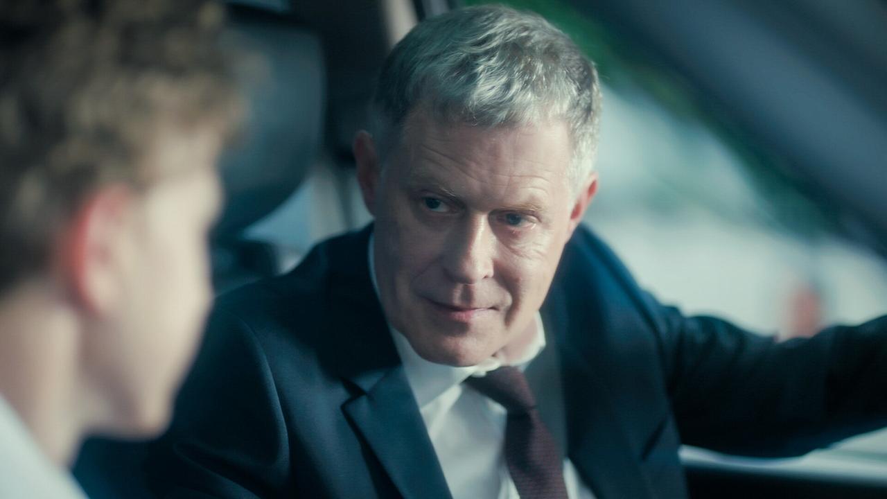 © ORF/MR Film Andreas Lust im Anzug sitzt im Auto und spricht mit einem Kind auf dem Beifahrersitz.