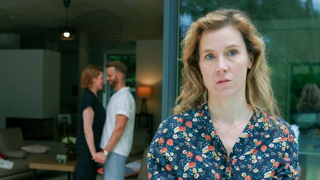 © ORF/MR Film/Petro Domenigg Franziska Hackl steht mit verschränkten Armen, während im Hintergrund Franziska Weisz und Mads Hjulmand Händchen haltend beisammenstehen.