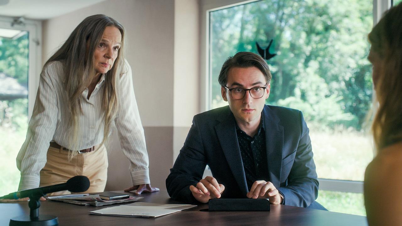 Sissy Höfferer und Tobias Resch befragen eine andere Person in einem Raum mit großen Fenstern mit Blick ins Grüne.