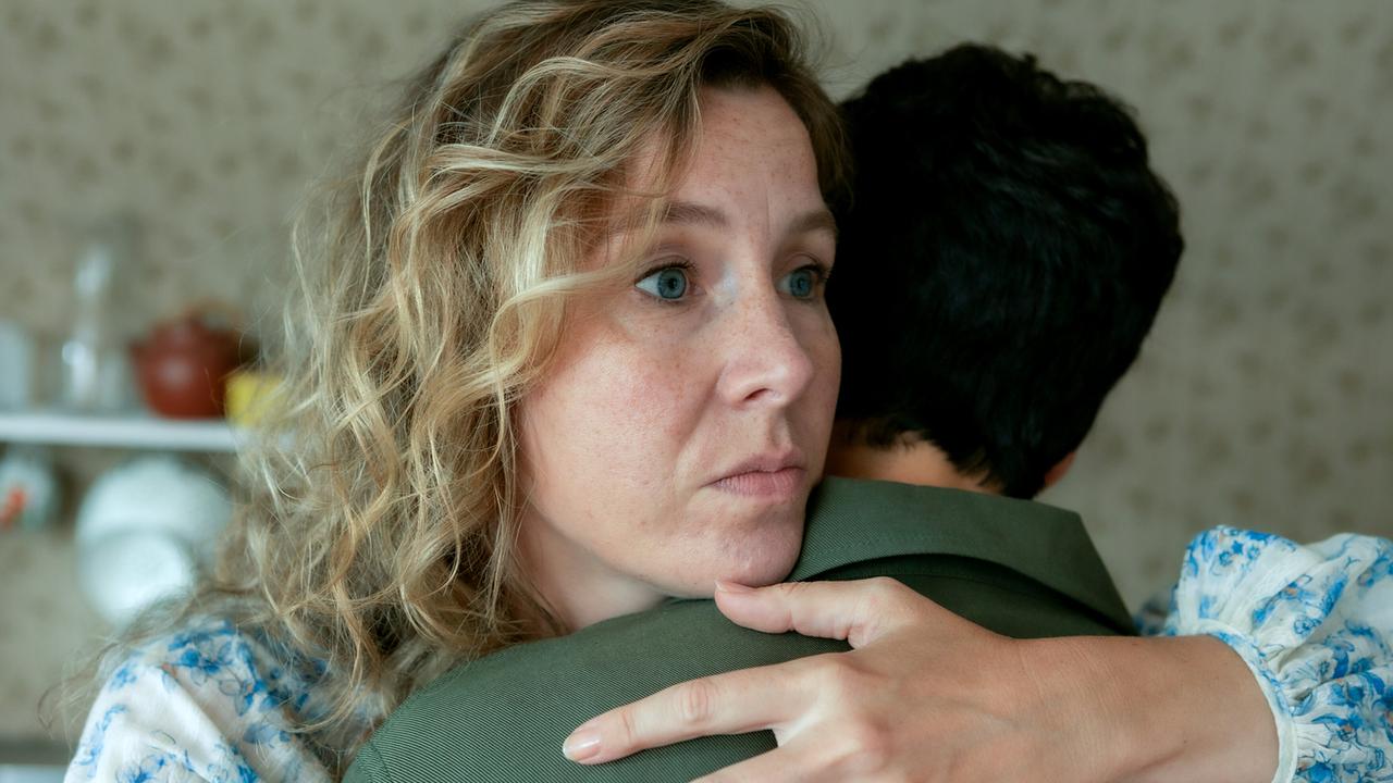 Franziska Hackl und Jasmin Gerat umarmen sich in einem Raum mit gemusterter Tapete.