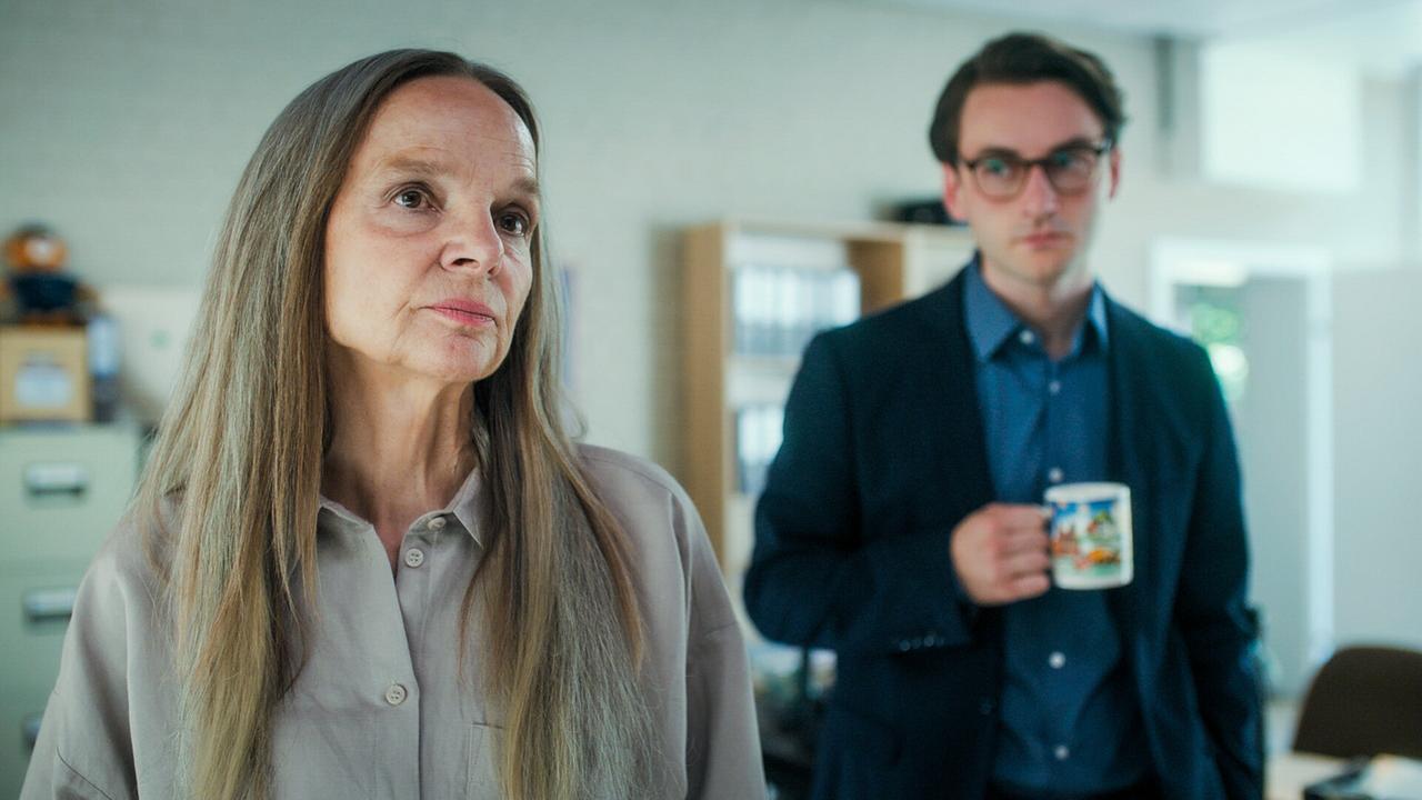 Sissy Höfferer und Tobias Resch mit einer Tasse in der Hand, stehen in ihrem Büro, im Hintergrund sind Aktenschränke und Regale.