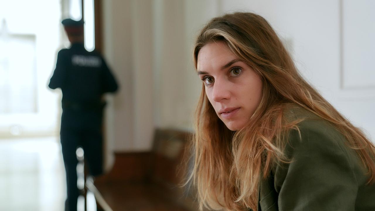 © ORF/MR Film/Petro Domenigg Maya Unger sitzt auf einer Bank im Gerichtsgebäude, im Hintergrund steht ein Polizist.
