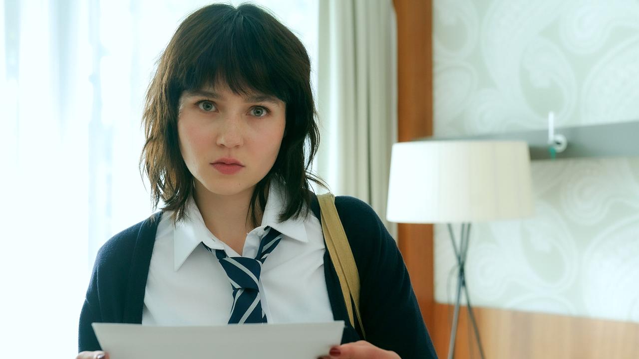 © ORF/MR Film/Petro Domenigg Paulina Hobratschk in Schuluniform und Krawatte steht in einem hellen Zimmer und hält ein Blatt Papier in den Händen.