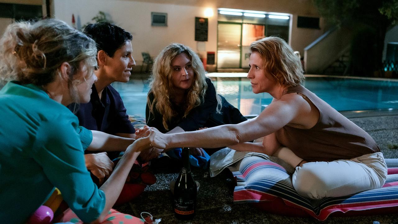 © ORF/MR Film/Anjeza Cikopano Franziska Hackl, Jasmin Gerat, Diana Amft und Franziska Weisz sitzen abends am Boden neben einem Pool, reichen sich die Hände, eine Flasche steht in der Mitte.