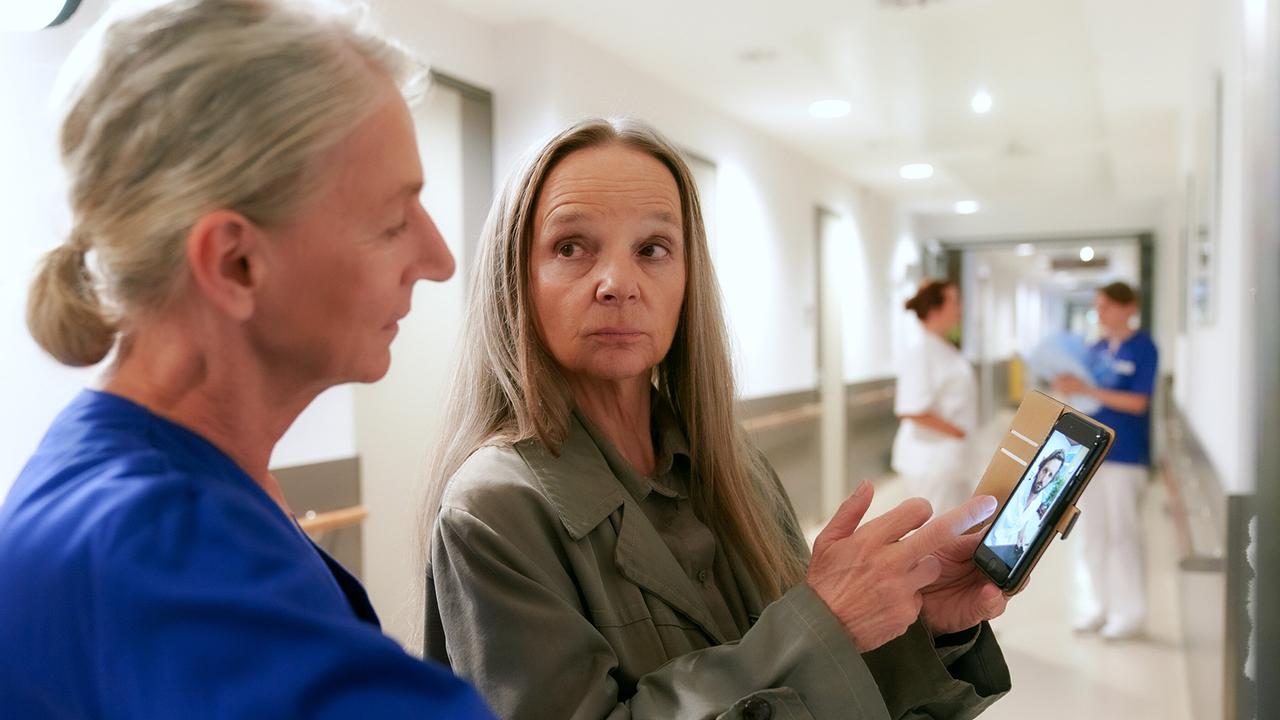 © ORF/MR Film/Petro Domenigg Sissy Höfferer zeigt ein Foto auf ihrem Smartphone einer Krankenschwester im Krankenhausflur.
