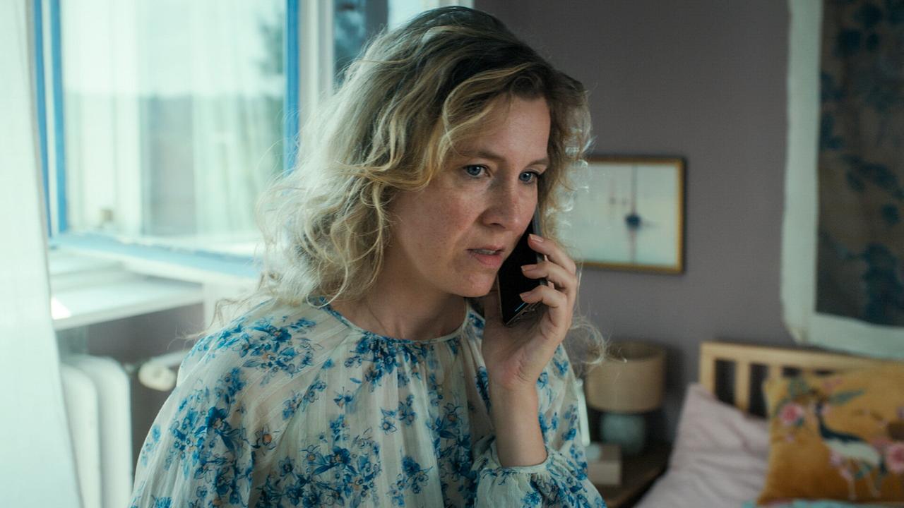 © ORF/MR Film Franziska Hackl in geblümter Bluse telefoniert in einem hellen Schlafzimmer.