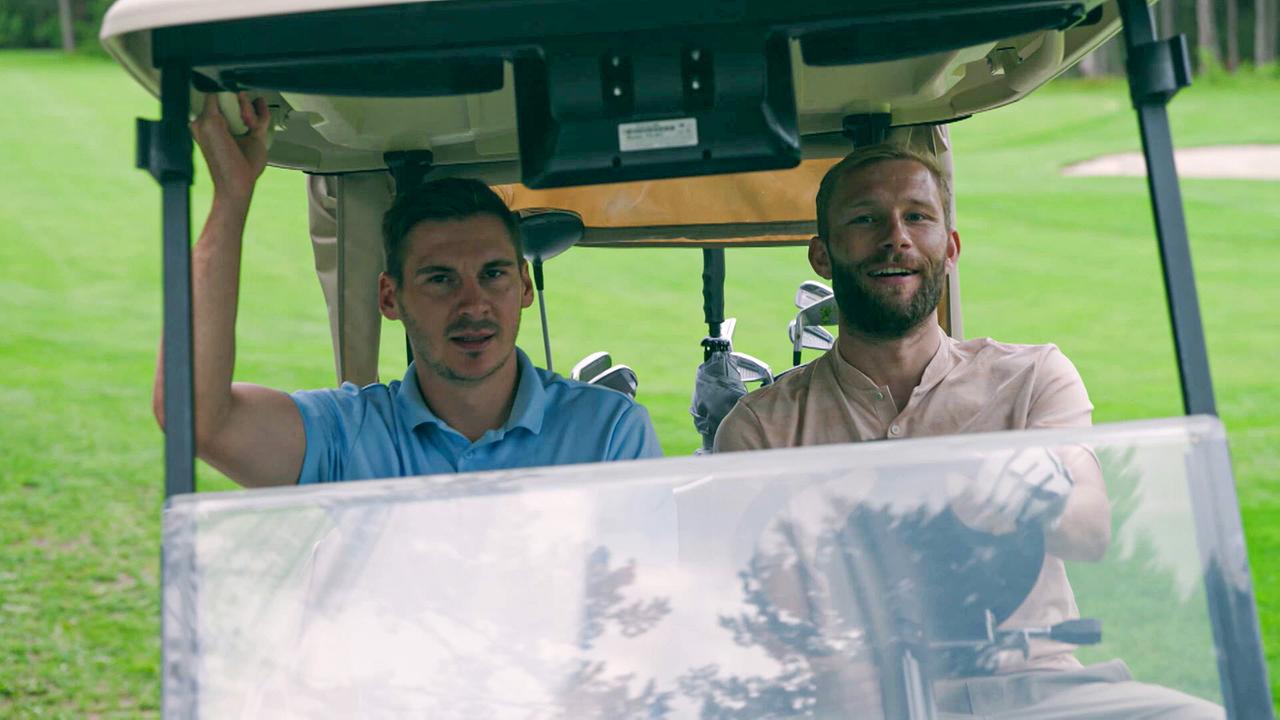 Maximilian Wöber und Konrad Laimer sitzen in einem Golfcart auf einem grünen Golfplatz und fahren über das Gelände.
