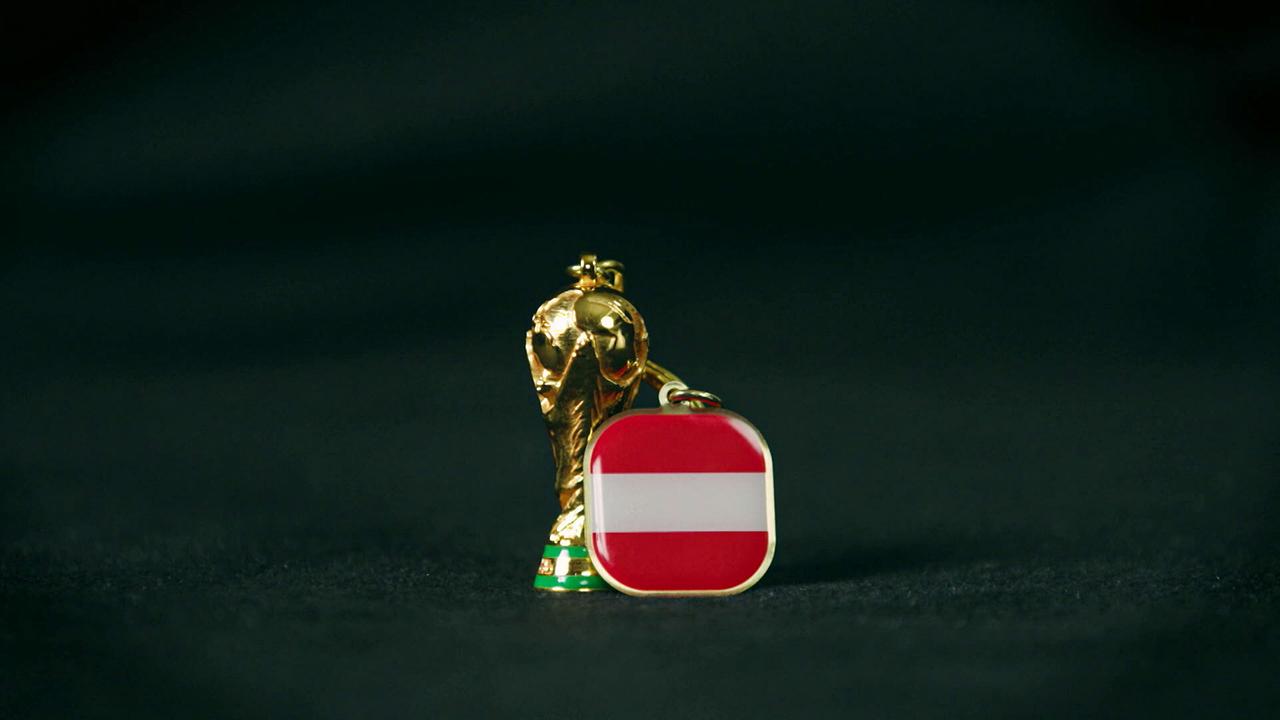 Teamchef Ralf Rangnick schenkt den Spielern einen eigens gestalteten Talisman, der symbolisch für Zusammenhalt, Fokus und den gemeinsamen Glauben an die historische Qualifikation steht: Ein kleiner goldener Pokal mit rot-weißem Emblem vor dunklem Hintergrund.