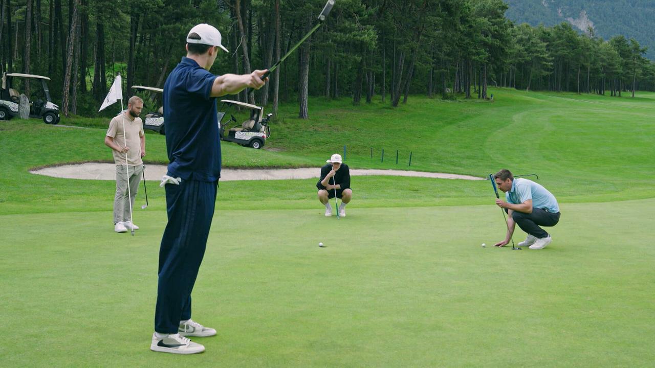 Vier Golfer stehen auf dem Putting Green und schauen konzentriert auf die Linie des Balls.