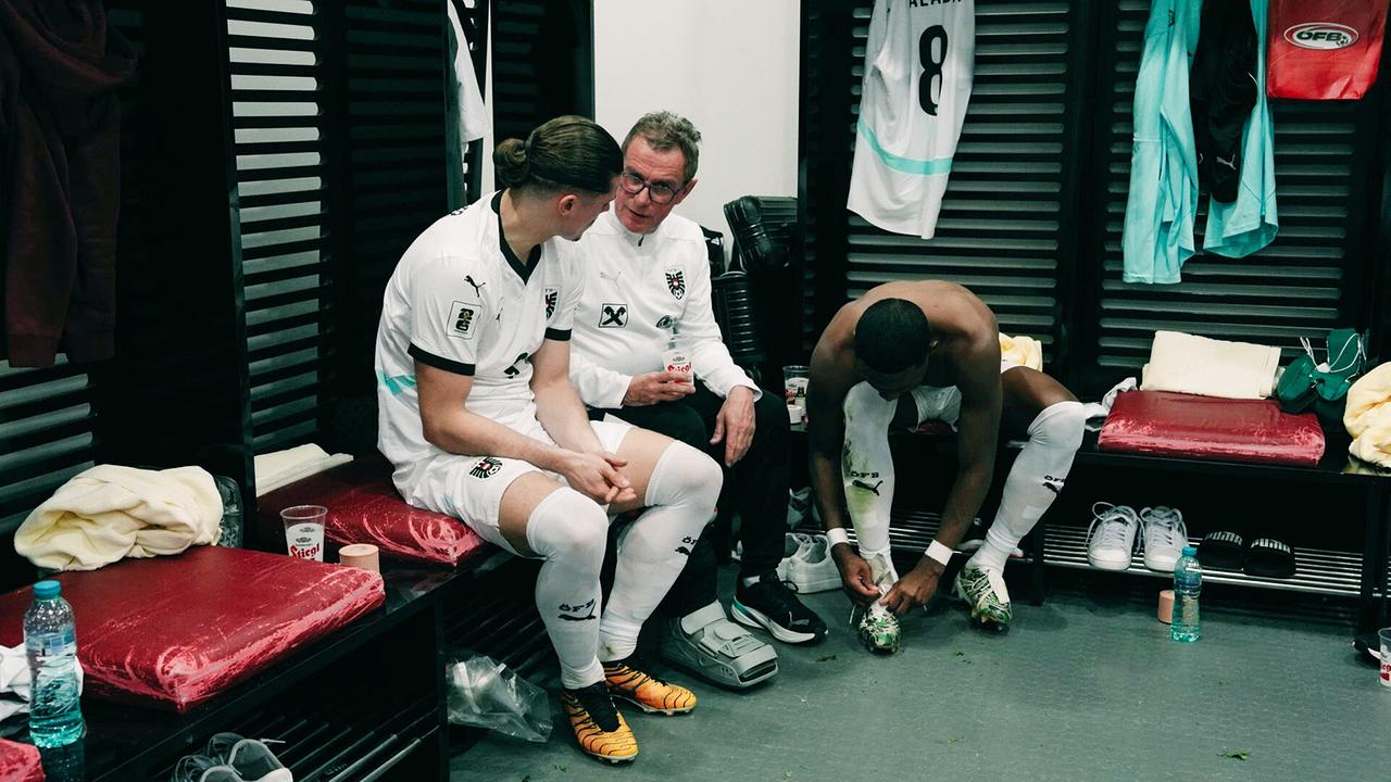 Teamchef Ralf Rangnick in der Umkleidekabine im Gespräch mit Marcel Sabitzer, während sich daneben während ein weiterer Spieler die Schuhe bindet.
