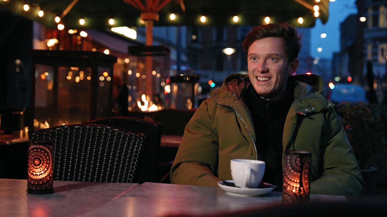 Michael Gregoritsch sitzt abends beim Interview in einem Café bei Kerzenlicht mit einer Tasse Kaffee.
