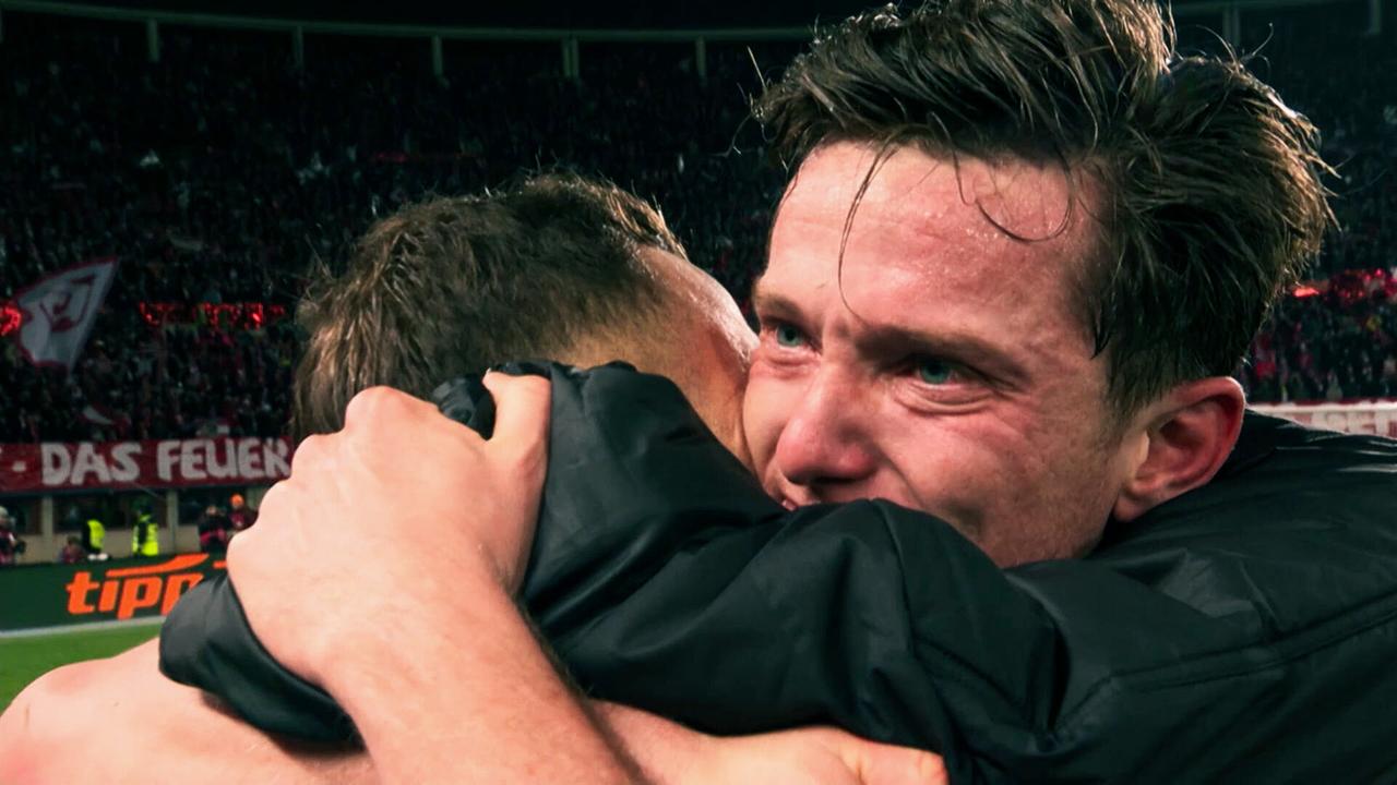 Michael Gregoritsch und ein Teamkollege umarmen sich emotional am Spielfeldrand nach einem Spiel.