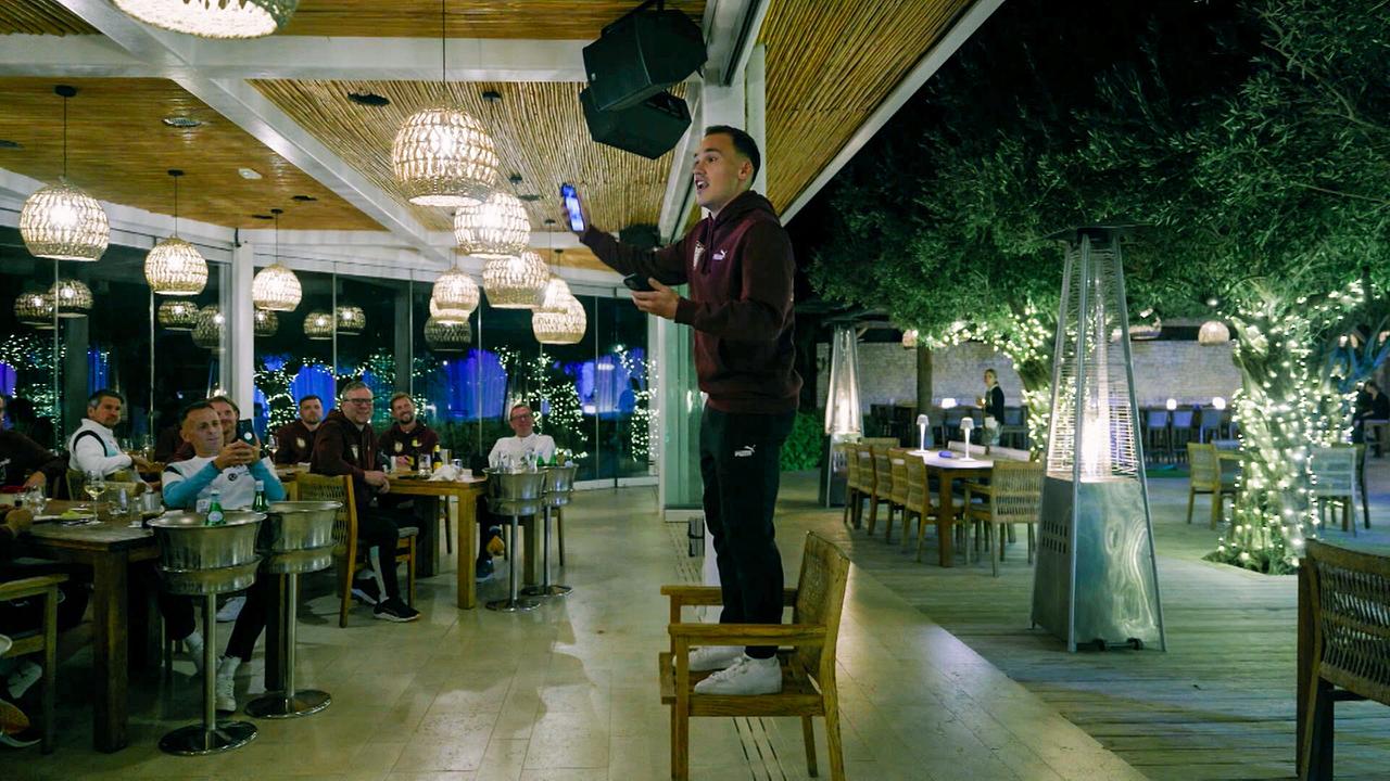 Nikolaus Wurmbrand rappt zum Einstand und zur Freude der Mannschaft, die vor ihm abends an Tischen in einem Restaurant sitzen, ein selbst komponiertes Lied.