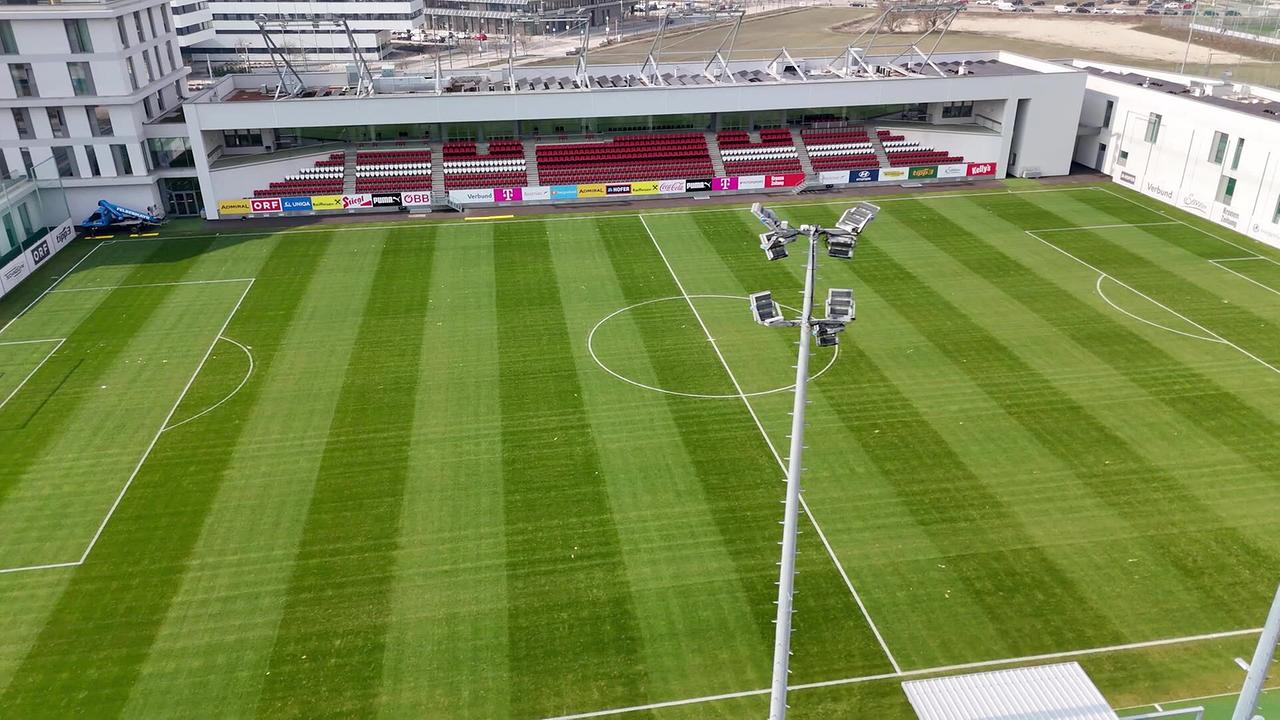 Ein leerer Fußballplatz mit Tribüne im neu gebauten ÖFB-Campus in der Seestadt wird aus der Vogelperspektive gezeigt.