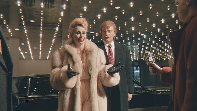 © ORF/DCM Film Distribution/Apprentice Productions Ontario Inc./Profile Productions 2 ApS/Tailored Films Ltd. Maria Bakalova als Ivana Trump in einem hellen Pelmantel und Sebastian Stan als Donald Trump in einem dunkelgrauen Mantel haben ihre schwarze Limousine verlassen und werden von Reportern vor dem Eingang eines Gebäudes erwartet