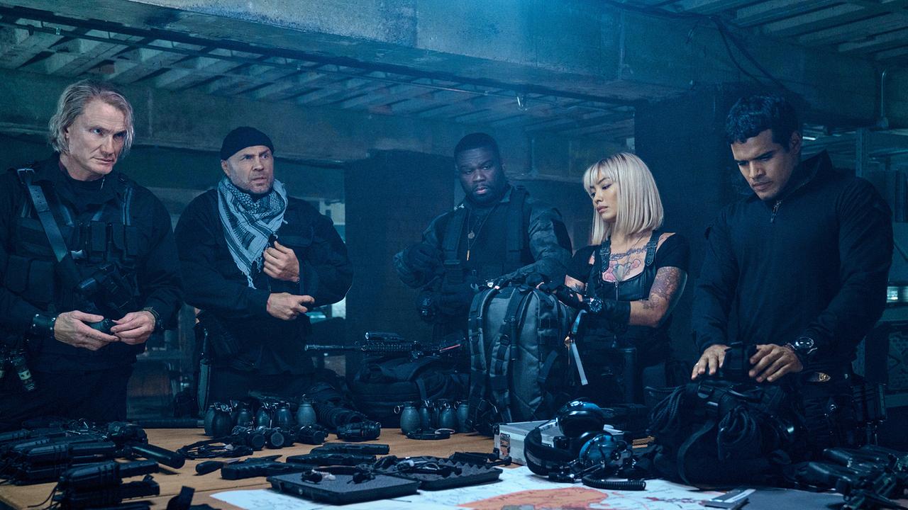 Vier Männer und eine Frau stehen um einen Tisch, auf dem Spezialausrüstung aller Art bereit liegen - alle sind schwarz bekleidet