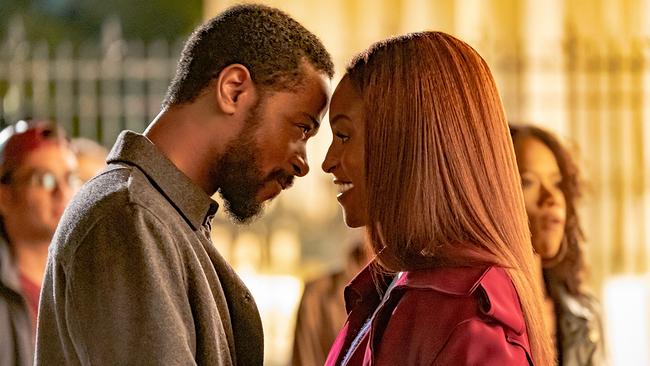 Michael und Mae stehen sich gegenüber, neigen ihre Köpfe zueinander und lächeln sich verliebt an