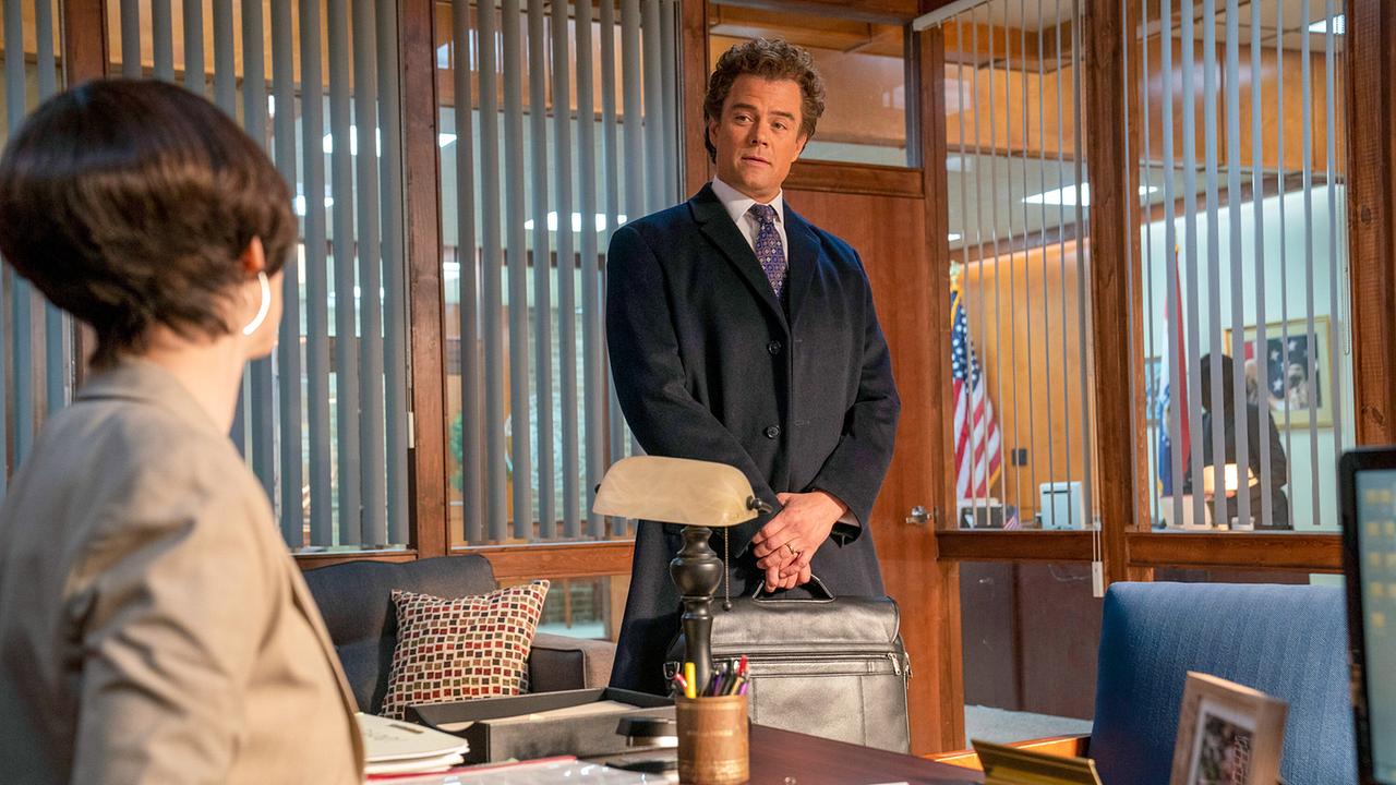 Anwalt Joel Schwartz steht im Mantel mit Hemd und Krawatte im Büro von Richterin Leah Askey, die an ihrem Schreibtisch sitzt, die beiden unterhalten sich miteinander