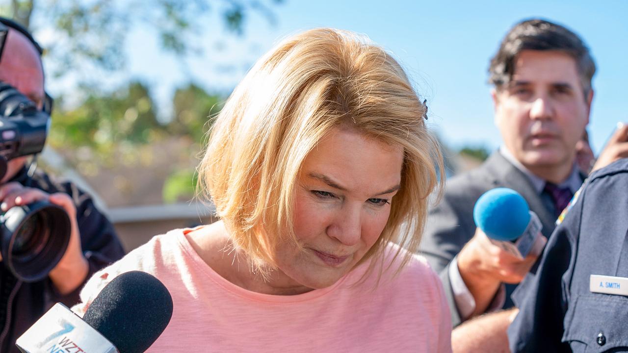 Renée Zellweger als Pam Hupp in rosafarbenen Pulli wird von Reporten belagert, Mikrofone und Kamera um sie herum, Pam blickt vor sich auf den Boden